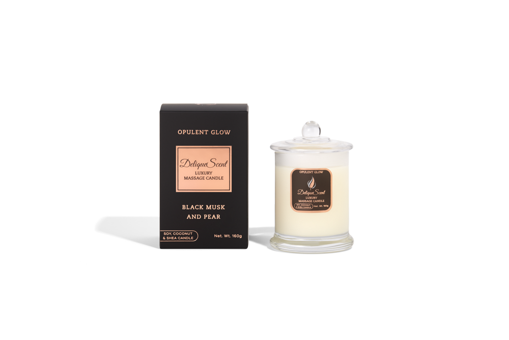 Body Safe, Organic Massage Candle in Opulent Glow fragrance which  is  Black Musk and Pear scent , Rose Gold Highlights on a black box next to the glass massage candle.